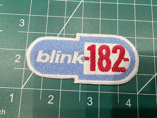 Patch with 'blink-182' logo on a green cutting mat with measurements.